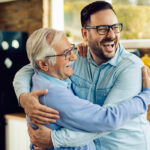 Cheerful mid adult man and his senior father embracing in the ki