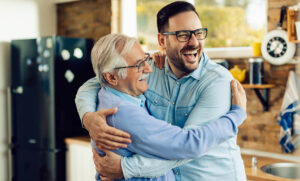 Cheerful mid adult man and his senior father embracing in the ki